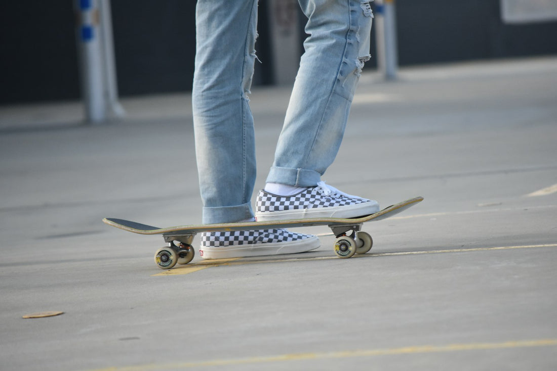 Skater standing on a skateboard wearing checkerboard slip-on shoes